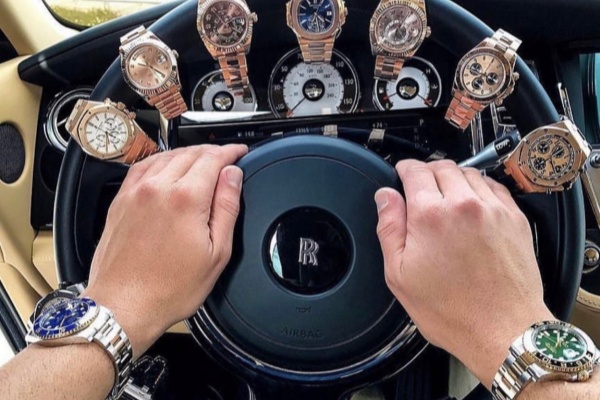 Man wearing a Rolex watch while driving a luxury car