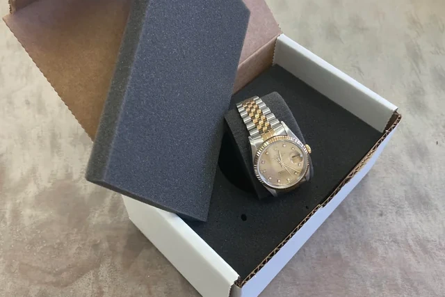 A person inspecting a newly arrived replica watch in its shipping box