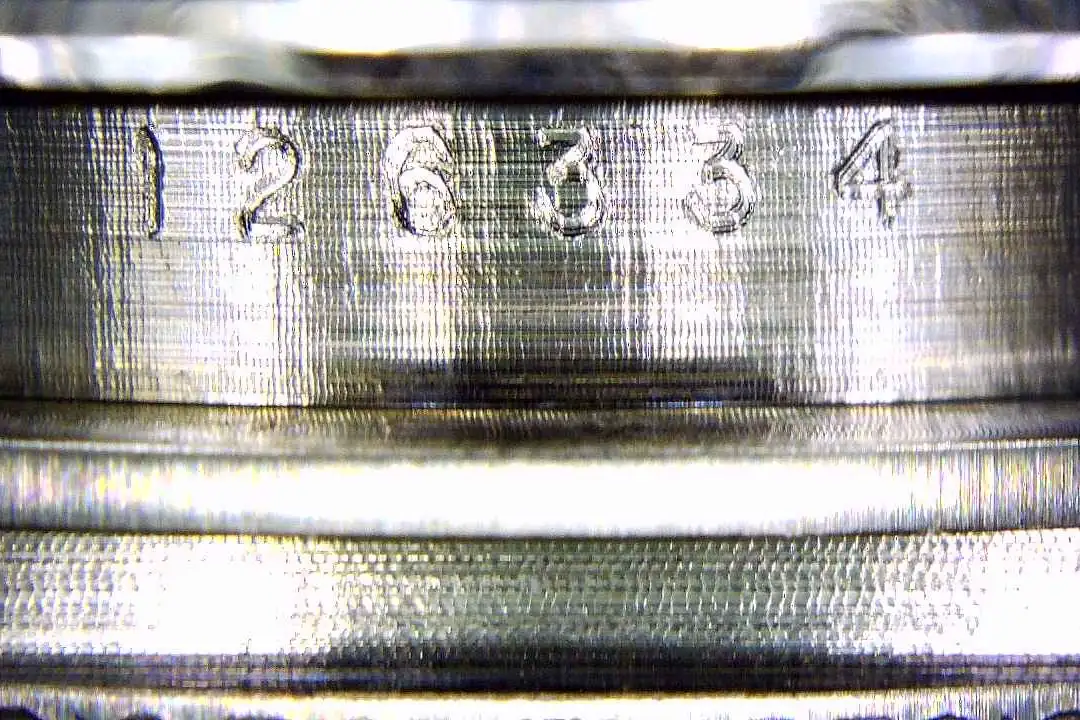 A close-up image showing the shallow laser engraving of a replica serial number